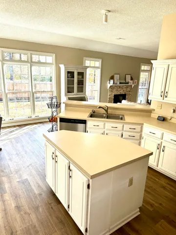 a kitchen with stainless steel appliances a stove top oven a sink a refrigerator white cabinets and wooden floor