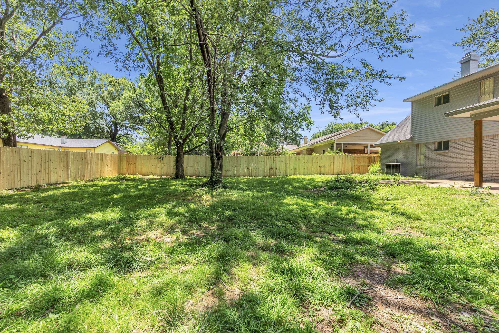 3314 Bright Ridge Cove Memphis, TN 38115 - Photo 16 of 16 Expansive grassy yard featuring a newly installed privacy fence, mature trees, and a covered patio area with a wood support column