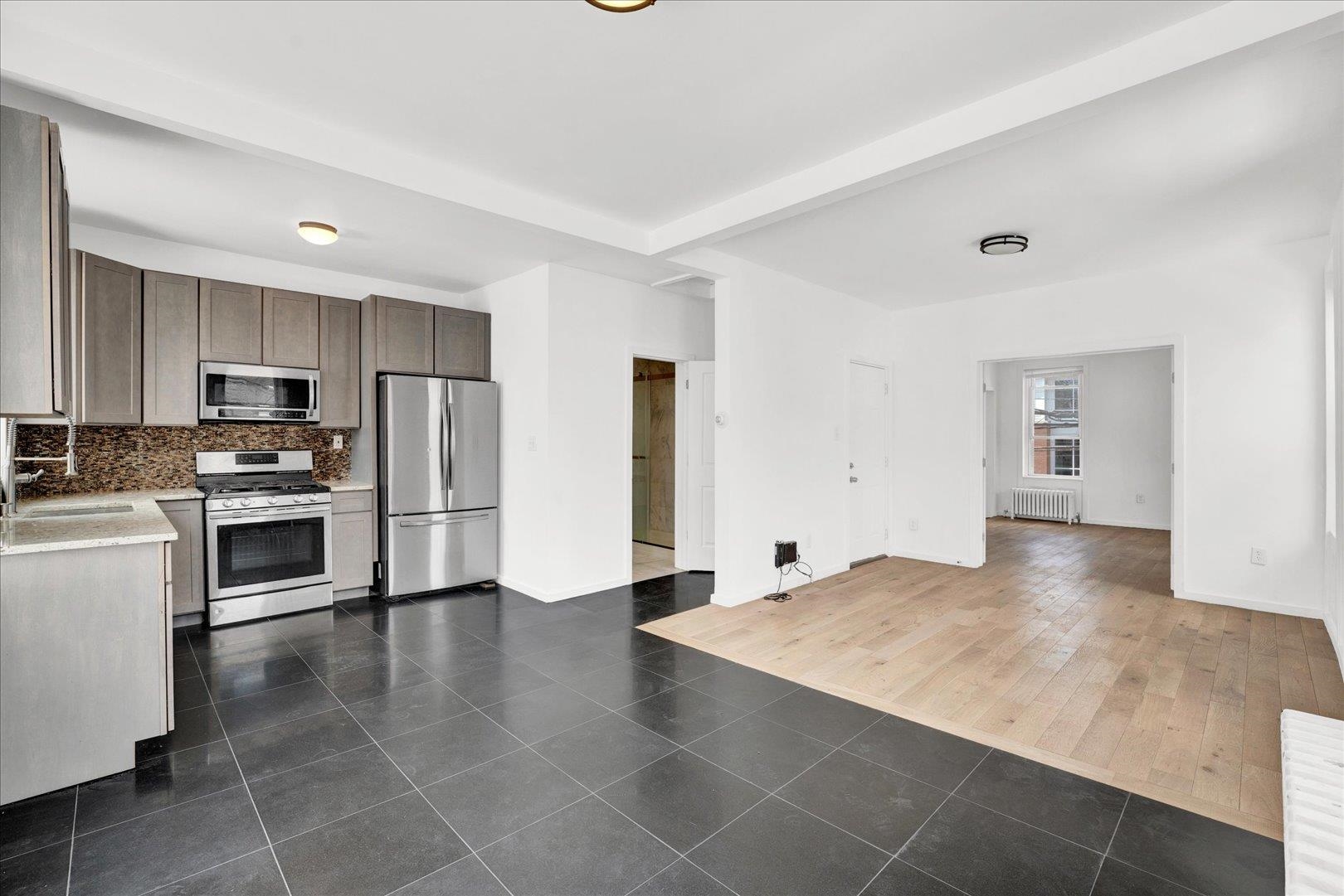 a view of a kitchen with wooden floor and electronic appliances