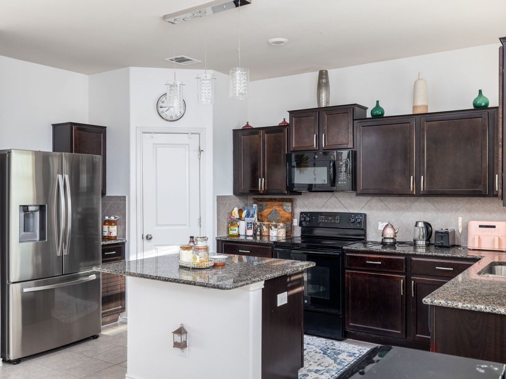 464 Druse Lane Jarrell, TX 76537 - Photo 11 of 26 a kitchen with stainless steel appliances granite countertop a stove refrigerator and microwave
