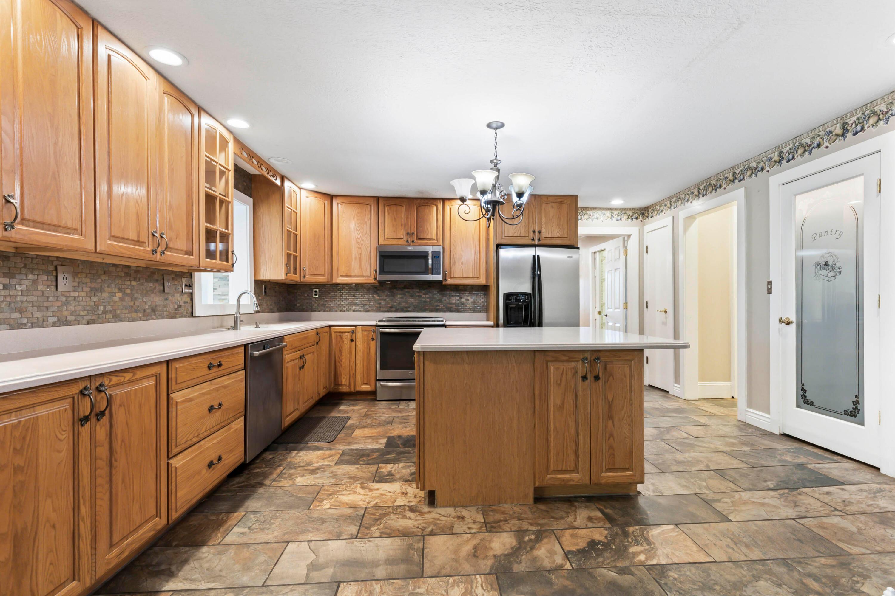 9495 Kilbourne Road Sunbury, OH 43074 - Photo 20 of 84 • Completely updated ~2003
• New slate flooring ~2014
• Tan painted walls
• Corian countertops
• 5’ x 5’ center island with
breakfast bar ledge
• 42” oak, raised panel cabinets
• New Bosch® dishwasher
~10/2014
• Extra deep, double bowl sink
with sprayer
• New Frigidaire® microwave
~2013
• New General Electric® electric
range ~2015
• New Whirlpool® refrigerator
~2012/2013
• Slate tile backsplash
• Insinkerator® disposal
• Can lighting
• Hanging light
• Pantry with glass front door
• Second pantry