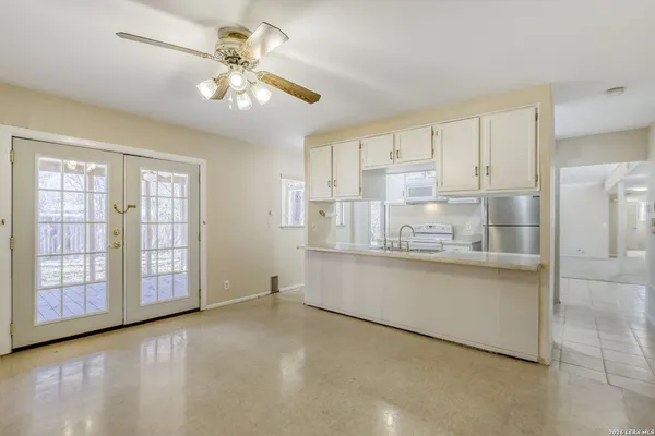 a large white kitchen with granite countertop a large window