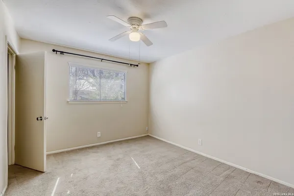 an empty room with a window and a fan