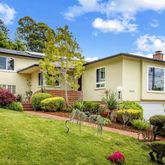 a yellow house with a big yard and potted plants