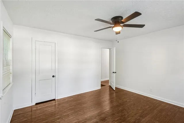 an empty room with wooden floor and ceiling fan