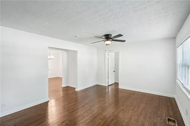 a view of an empty room with a window and wooden floor
