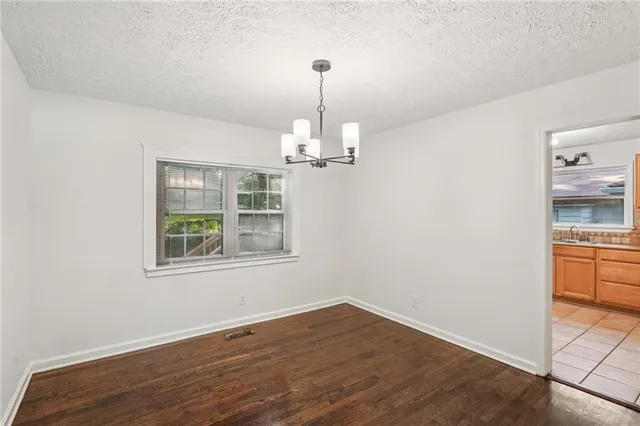 an empty room with wooden floor cabinet and windows