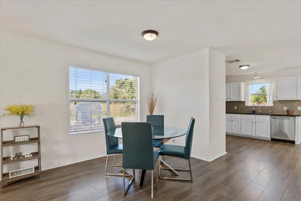 a kitchen with stainless steel appliances granite countertop a refrigerator a stove top oven a sink dishwasher and white cabinets with wooden floor