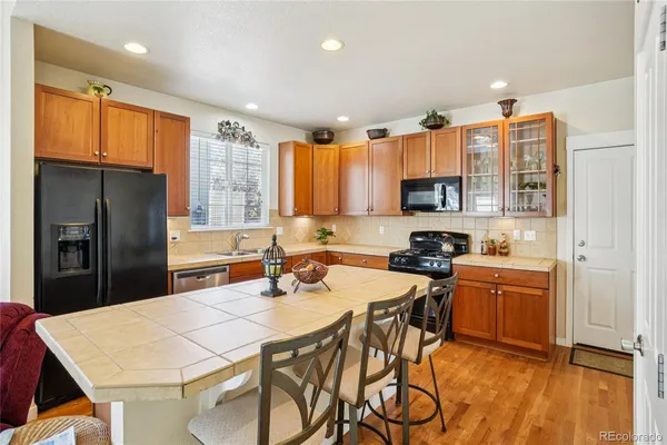 a kitchen with stainless steel appliances granite countertop a refrigerator a stove top oven a sink dishwasher and white cabinets with wooden floor