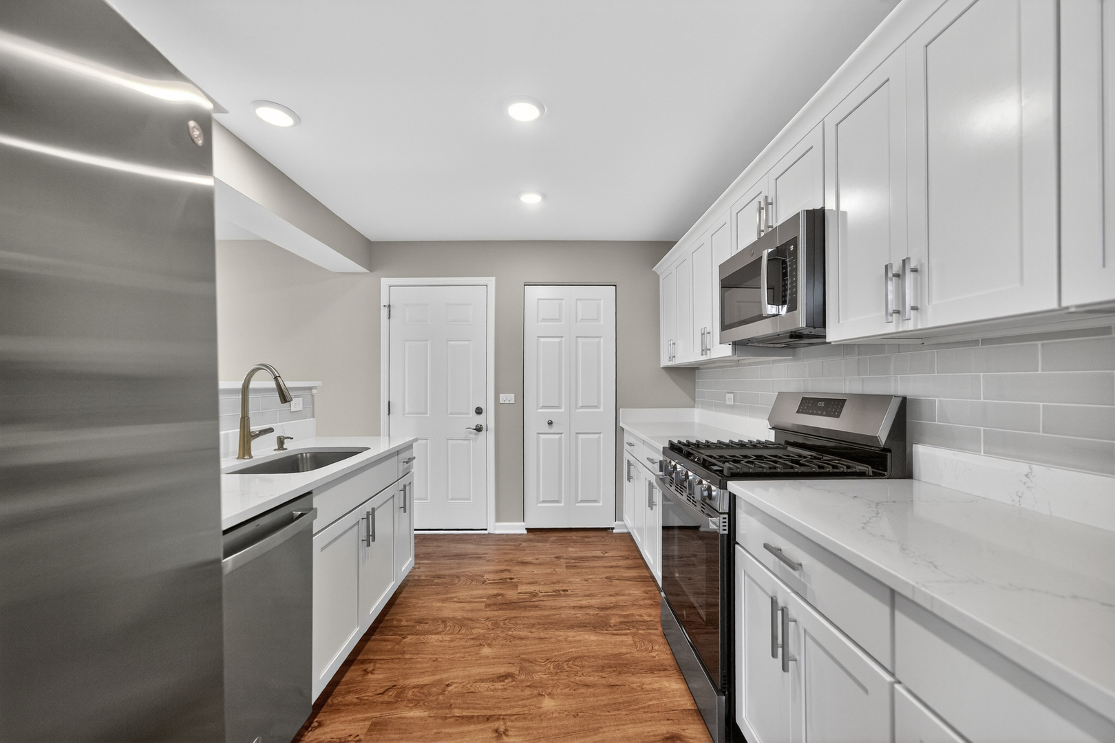 446 Cromwell Circle, Unit 4 Bartlett, IL 60103 - Photo 6 of 18 a kitchen with stainless steel appliances granite countertop a sink and dishwasher a stove top oven with wooden floor
