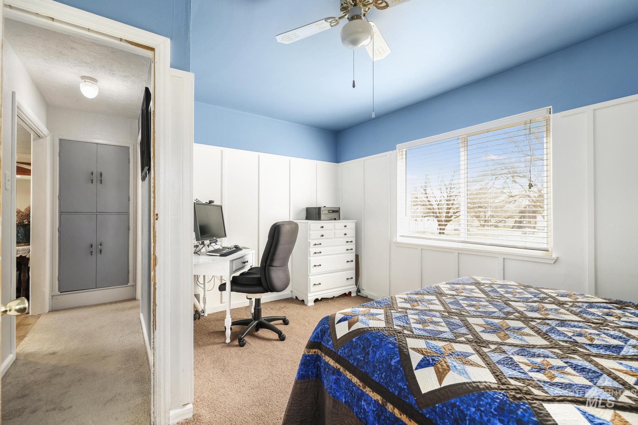 19591 Queen Crown Road Carey, ID 83320 - Photo 12 of 37 Interior room featuring a large window with horizontal blinds, a ceiling fan with integrated lighting, and board and batten wainscoting