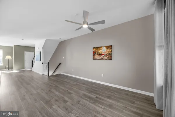 an empty room with wooden floor and ceiling fan