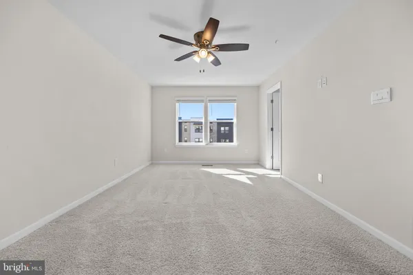 an empty room with a ceiling fan and window