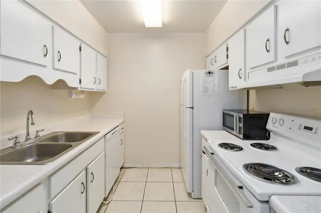 a kitchen with stainless steel appliances a white stove top oven a sink and a refrigerator