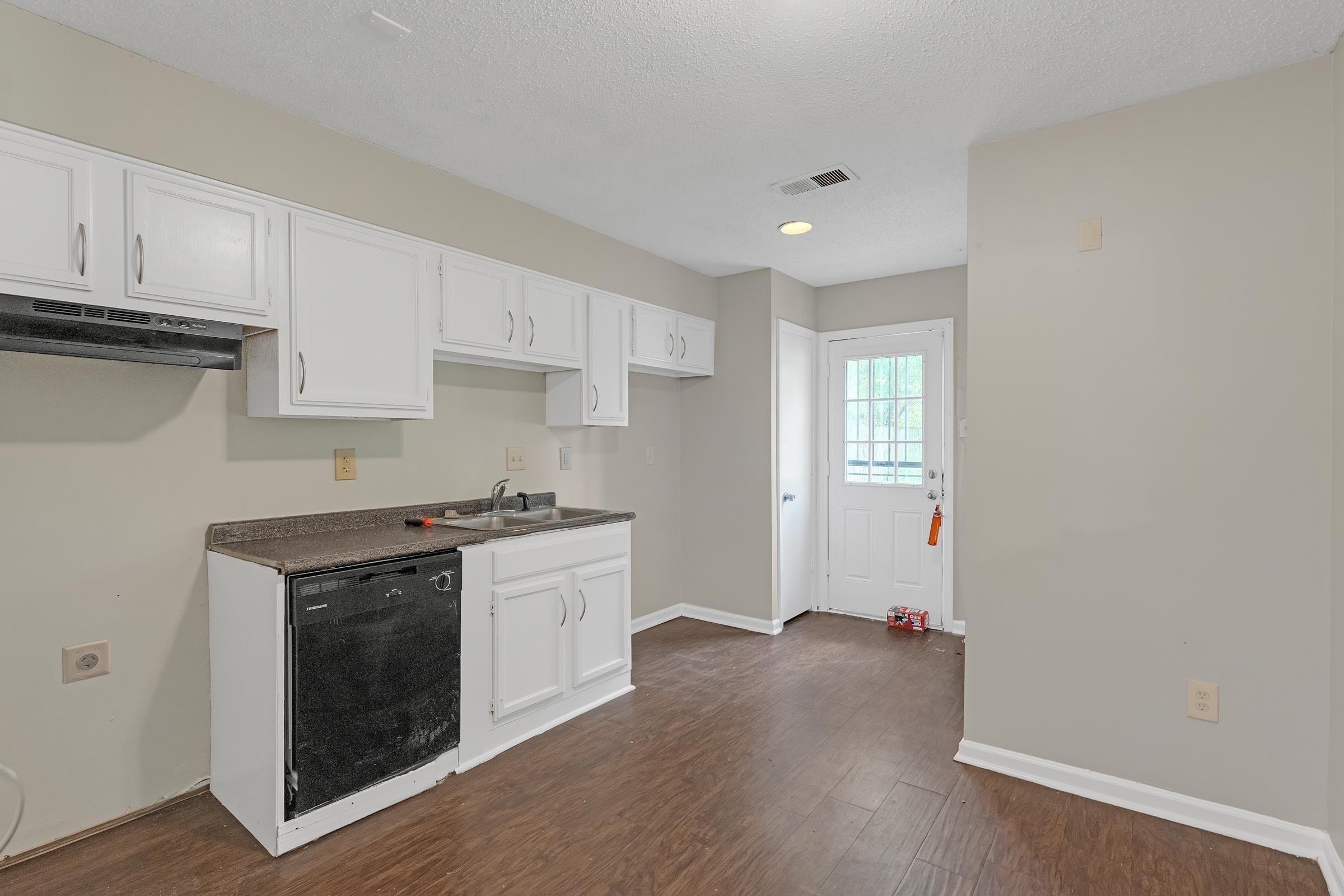 6128 Raintree Drive Memphis, TN 38115 - Photo 9 of 30 Kitchen featuring white cabinets, dark countertops, dark wood finished floors, dishwasher, and a textured ceiling