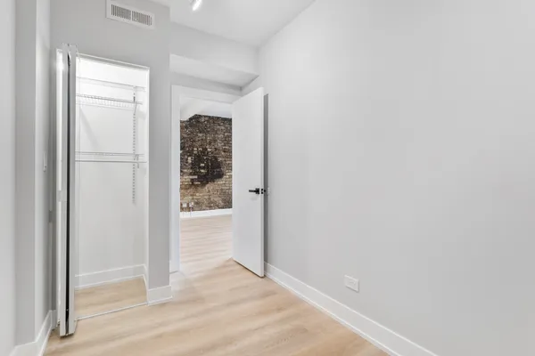 an empty room with wooden floor closet and windows