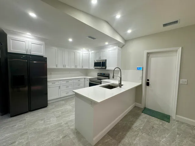 a large kitchen with kitchen island a sink stainless steel appliances and cabinets