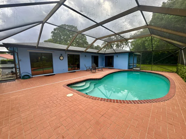 a view of a swimming pool with a patio and a yard