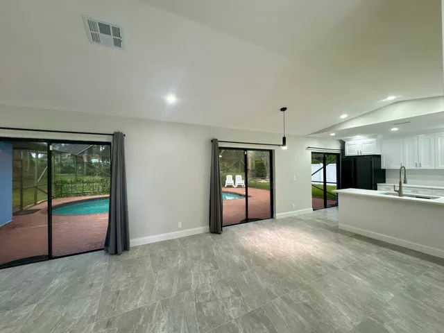 a view of an empty room with kitchen and a window