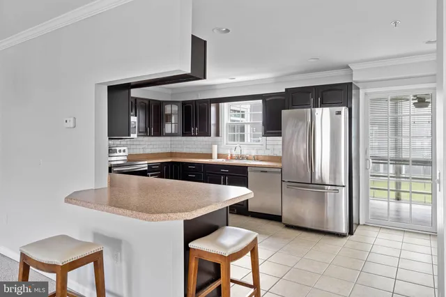 a kitchen with stainless steel appliances granite countertop a refrigerator a stove a sink a dining table and chairs
