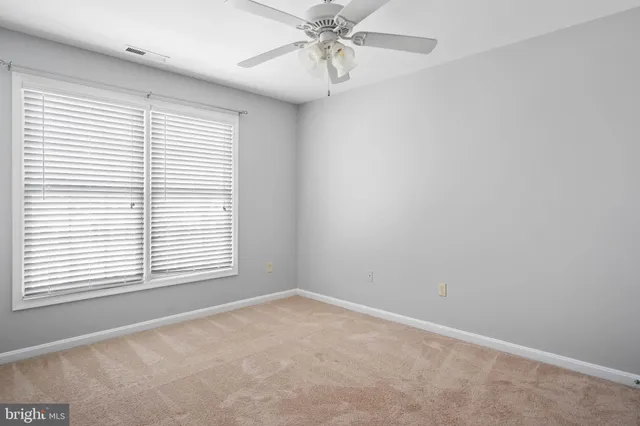 an empty room with a window and a fan