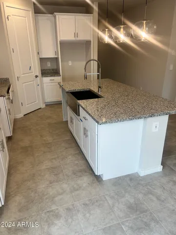 a kitchen with granite countertop a sink and white cabinets