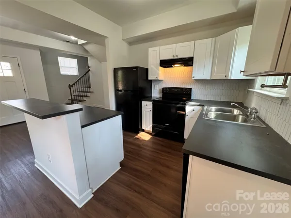 a kitchen with granite countertop a sink a counter top space stainless steel appliances and cabinets