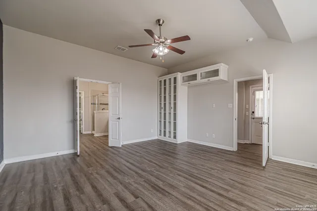 an empty room with wooden floor and windows