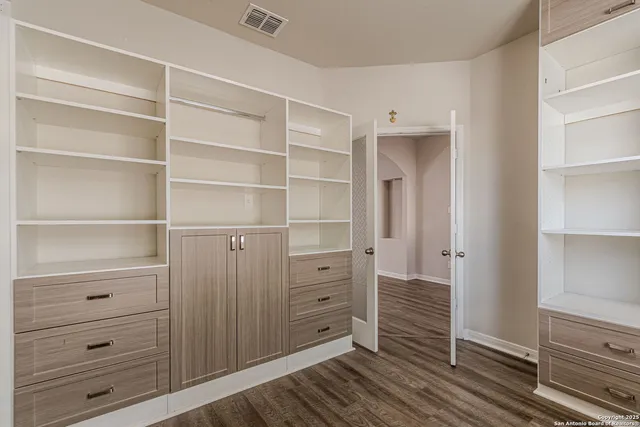 an empty room with wooden floor cabinet and windows