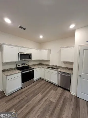 a kitchen with granite countertop a refrigerator and a stove top oven