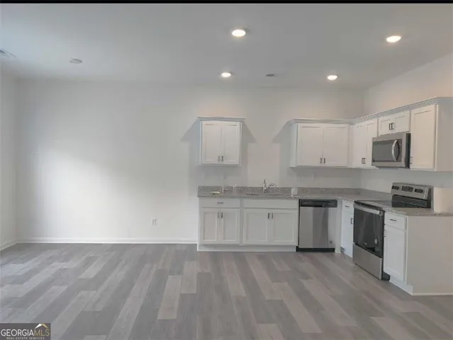 a large kitchen with granite countertop a stove top oven a sink and dishwasher with wooden floor