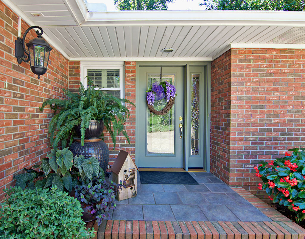 A welcoming front entrance features timeless brick siding, tiled flooring, and a decorative glass door.