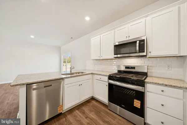 a kitchen with granite countertop white cabinets sink and stainless steel appliances