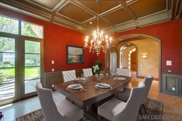 a view of a dining room with furniture a chandelier and large windows