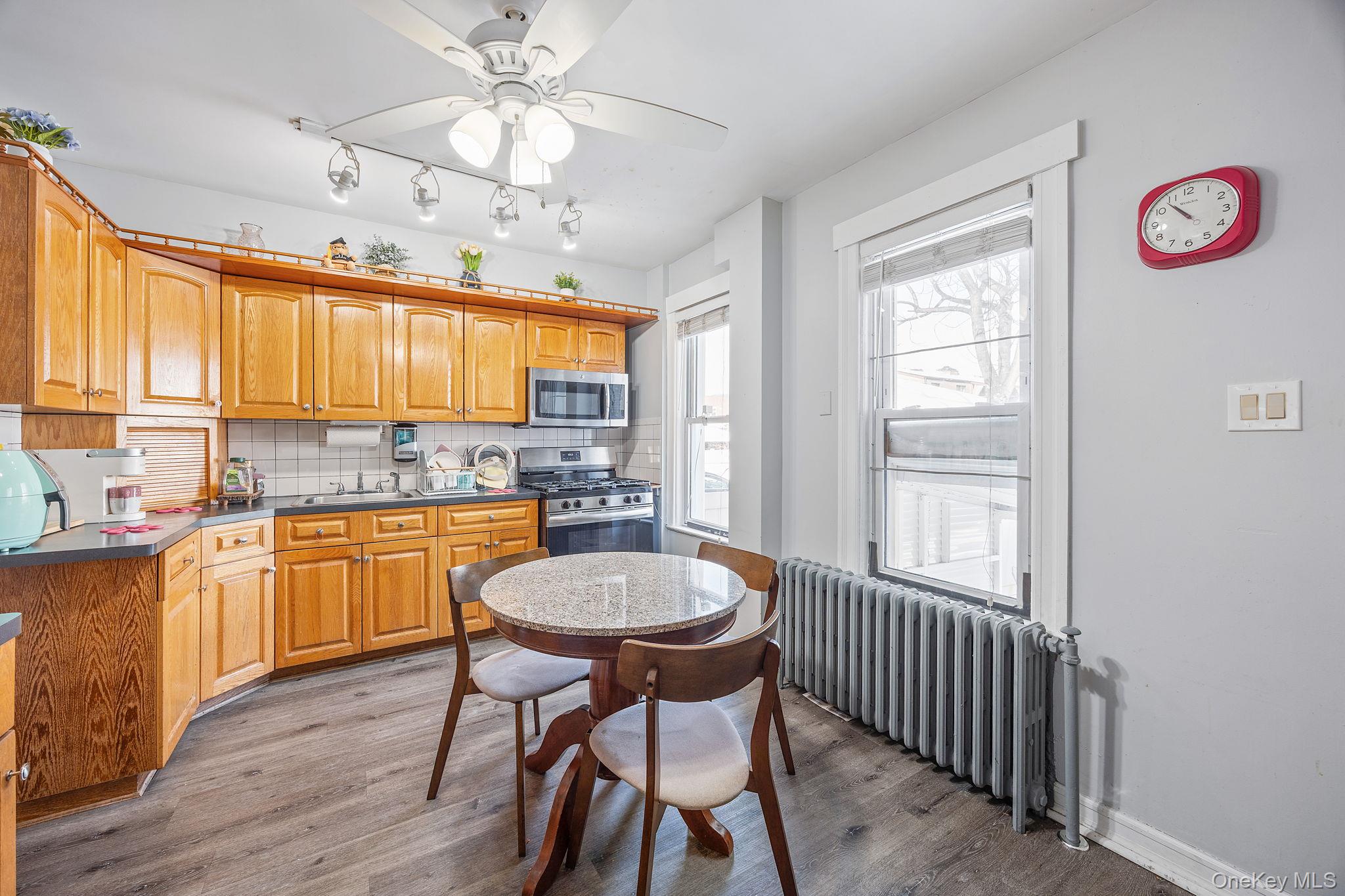 72-15 Juniper Valley Road Queens, NY 11379 - Photo 5 of 15 a kitchen with a dining table chairs wooden cabinets and white appliances