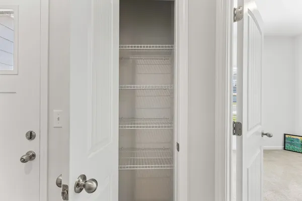 a view of an empty room with kitchen and window