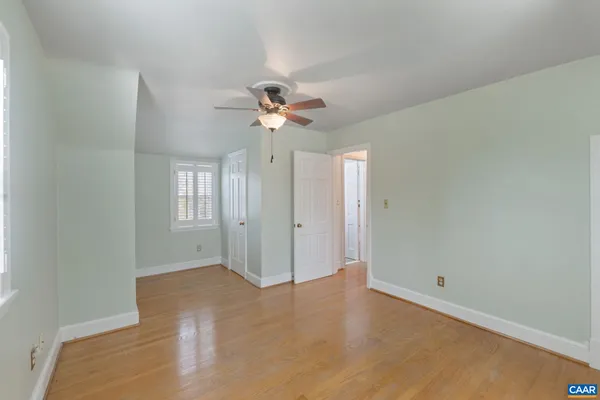 a view of an empty room with chandelier fan and a window