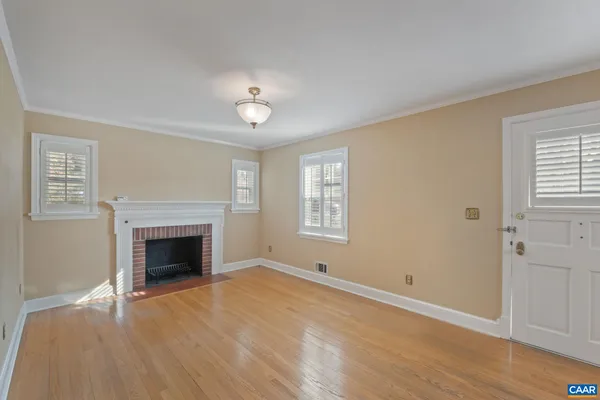 an empty room with windows fireplace and wooden floor
