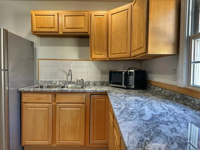 a kitchen with granite countertop a sink a stove and cabinets