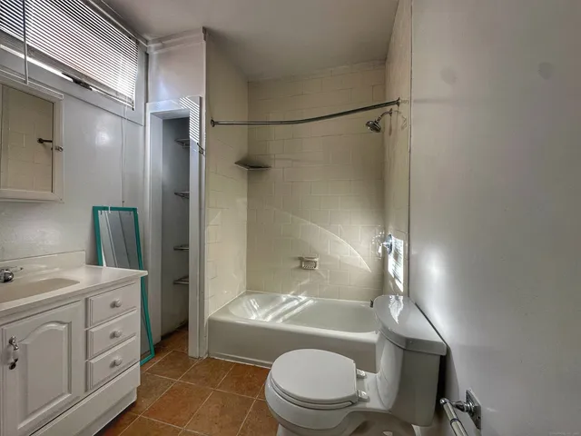 a bathroom with a granite countertop bathtub shower sink vanity and toilet
