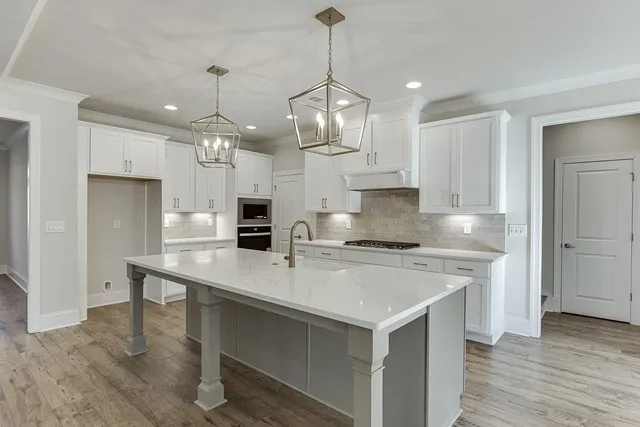 a large kitchen with kitchen island a stove a sink a refrigerator and a wooden floor