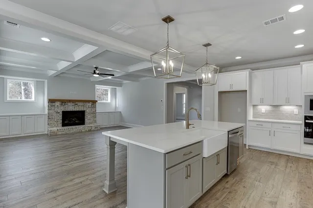 a kitchen with a sink chandelier and wooden floor