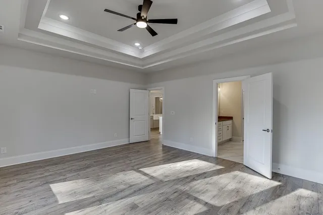 an empty room with wooden floor and ceiling fan