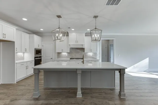 a kitchen with kitchen island granite countertop a sink cabinets a refrigerator and a stove