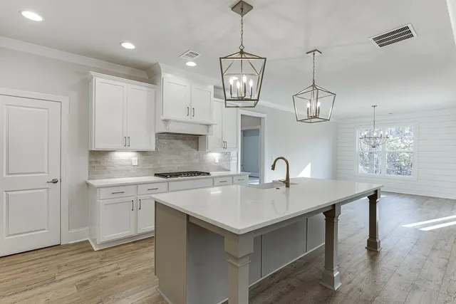 a kitchen with stainless steel appliances granite countertop a sink a stove and a wooden floors