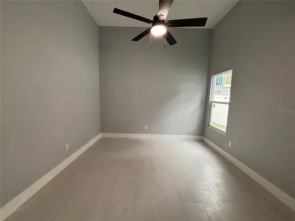 an empty room with a window and ceiling fan