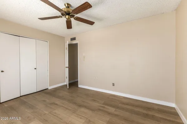 an empty room with wooden floor and fan