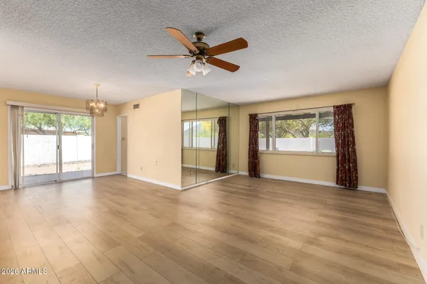 a view of an empty room with a window and wooden floor