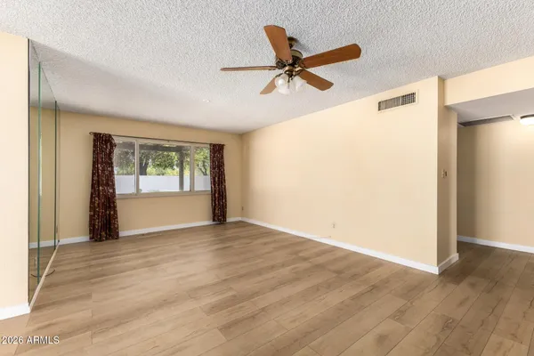 a view of an empty room with wooden floor and a window