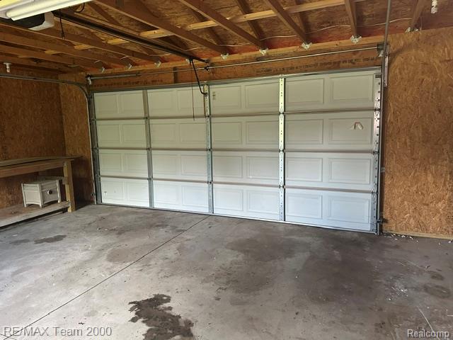 30600 Fort Road Rockwood, MI 48173 - Photo 16 of 28 Garage space featuring a paneled overhead door, concrete flooring, exposed ceiling joists, and oriented strand board walls